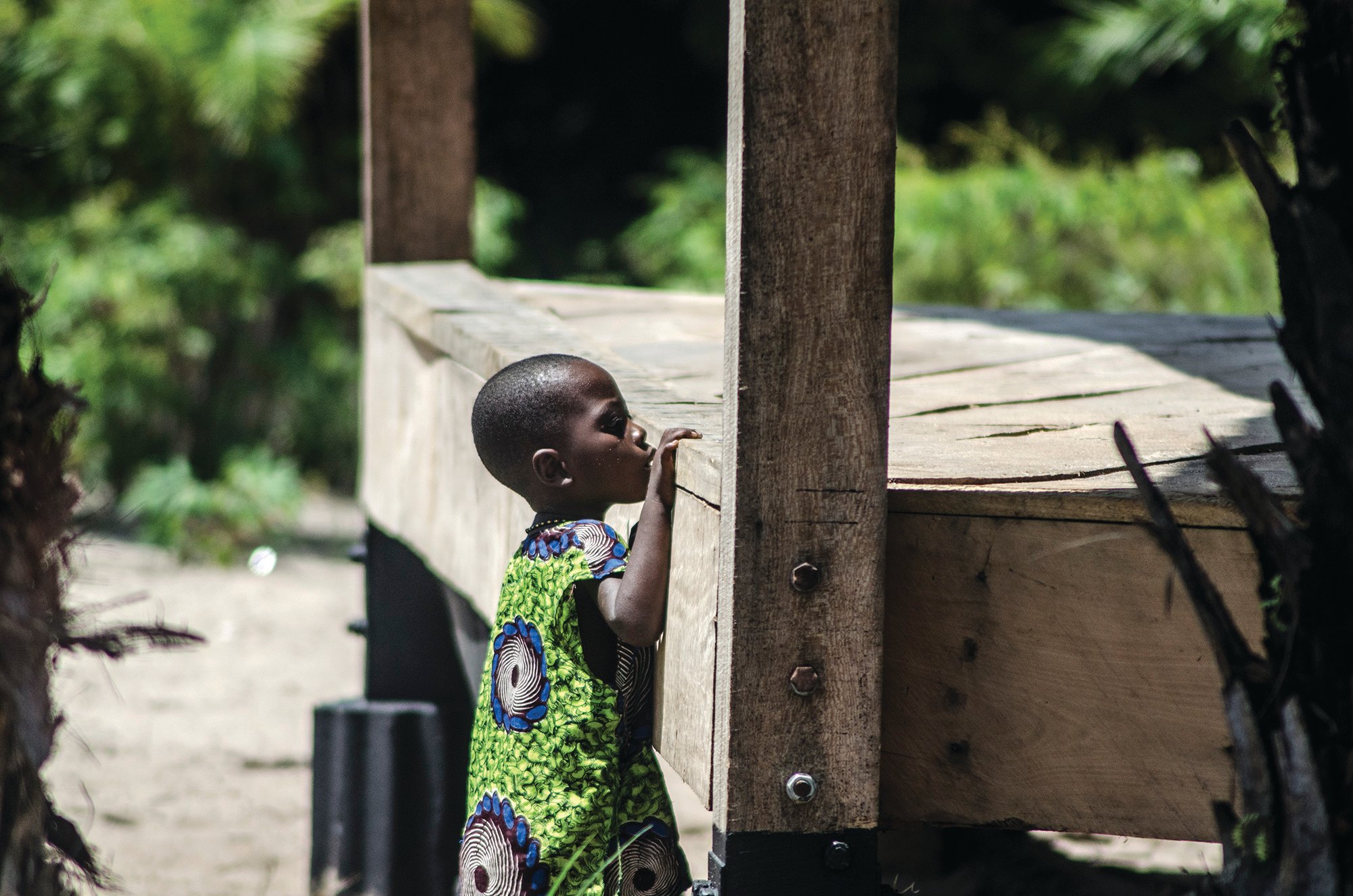 Child standing beside the edge of a raised timber floor and a wooden support post.
