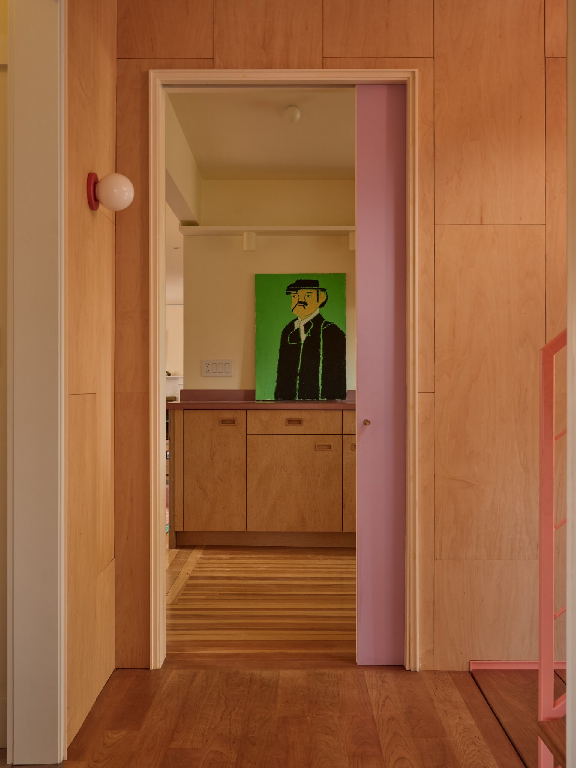 Wood-lined passage with contrasting pink doorway trim and a cabinet at the far end.