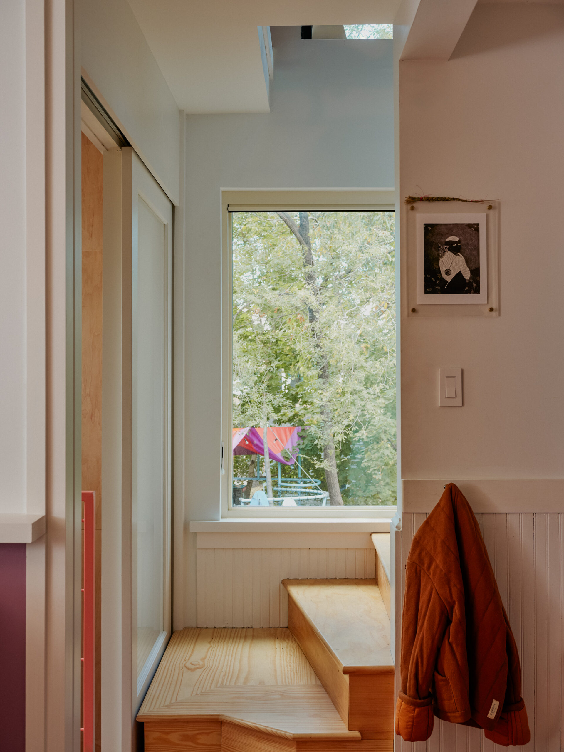 Narrow entry space with a built-in wooden window seat and a skylight above.