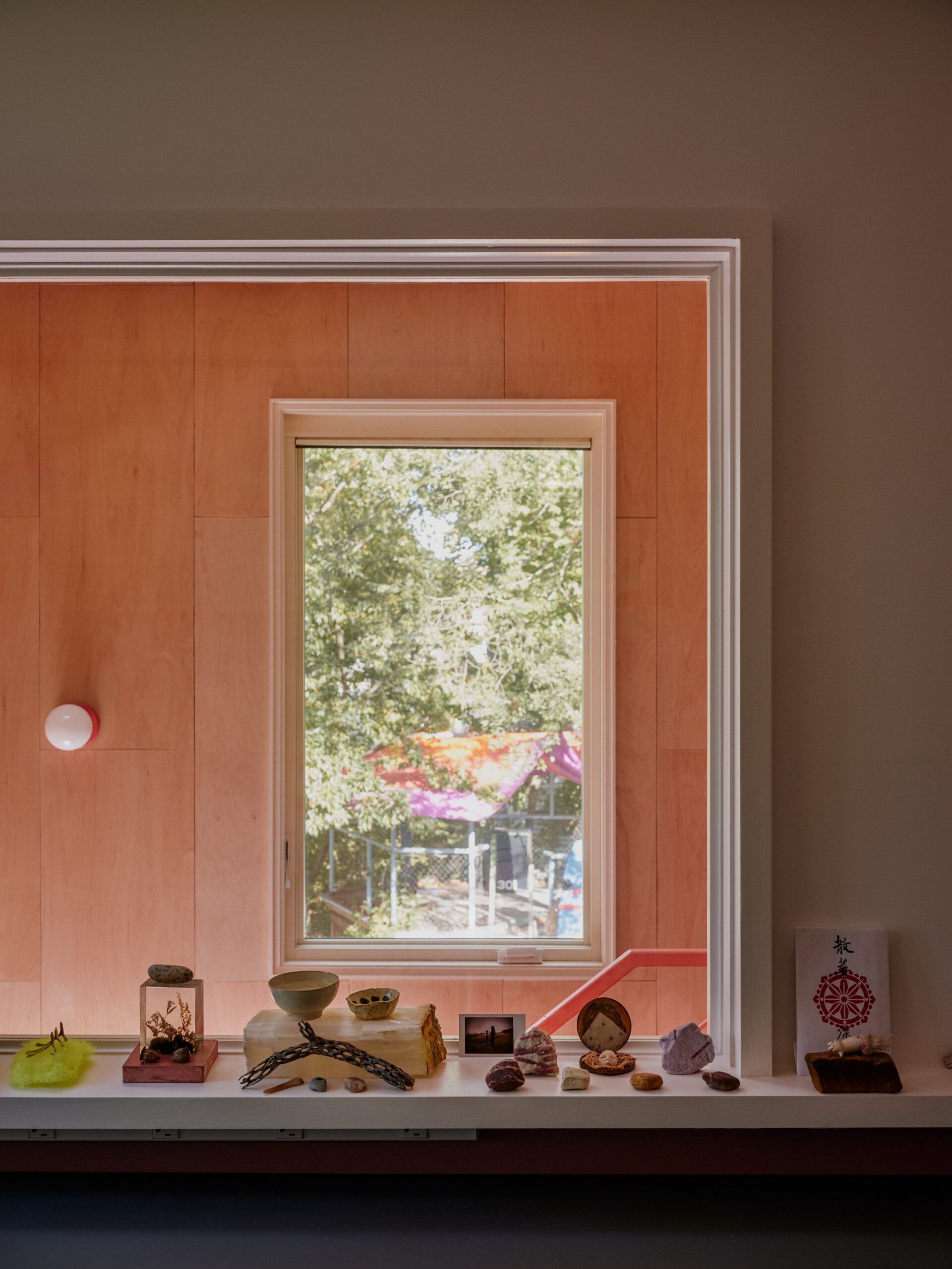 Kitchen window framed by wood paneling above a counter displaying small objects.